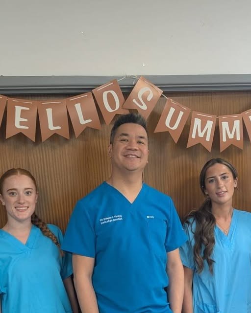 The clinic team in their blue scrubs under a Hello Summer banner