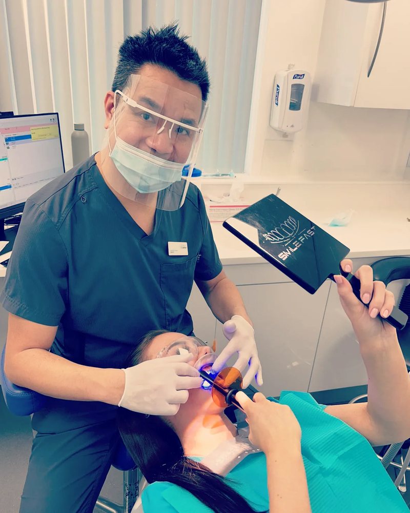 Dr Ed Young treating a patient with the curing light — patient holding the SmileFast mirror